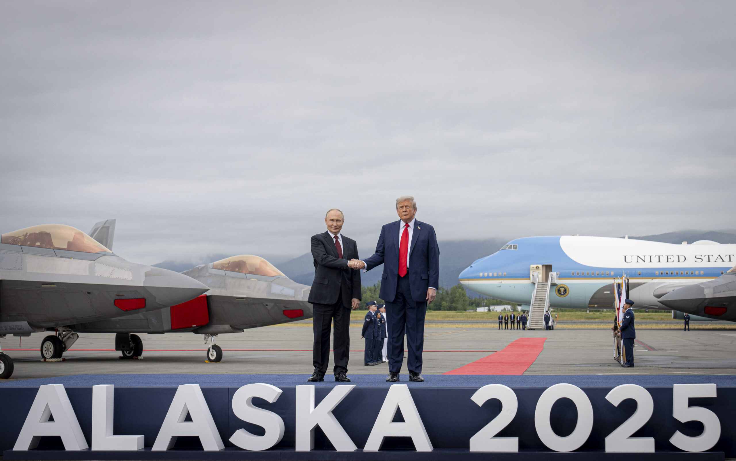 Vladímir Putin y Donald Trump se dan la mano en la base Elmendorf-Richardson, en Alaska, con cazas F-22 y el avión Air Force One de fondo
